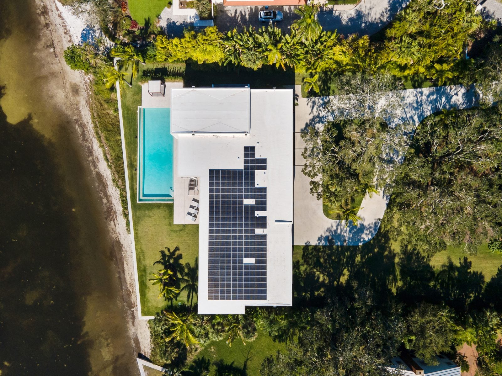 Bentonhaus II seen from directly above: roof planes, rooftop solar array, pool, drive and the bay beyond